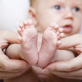 Newborn baby feet in mother's hands.